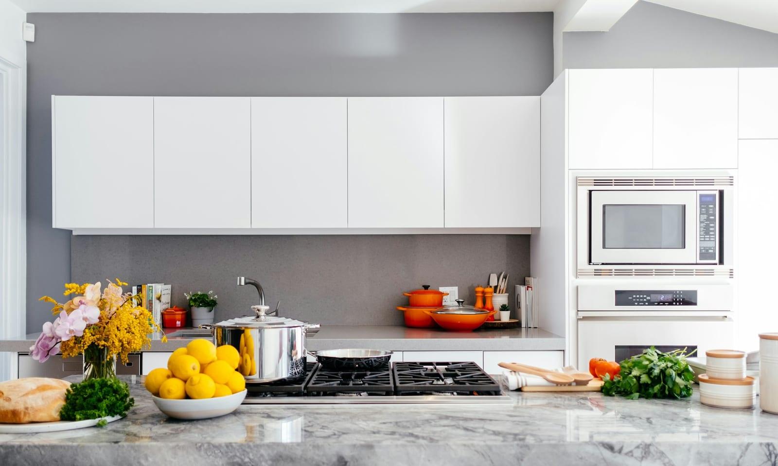 White contemporary kitchen with grey backsplash and marble island